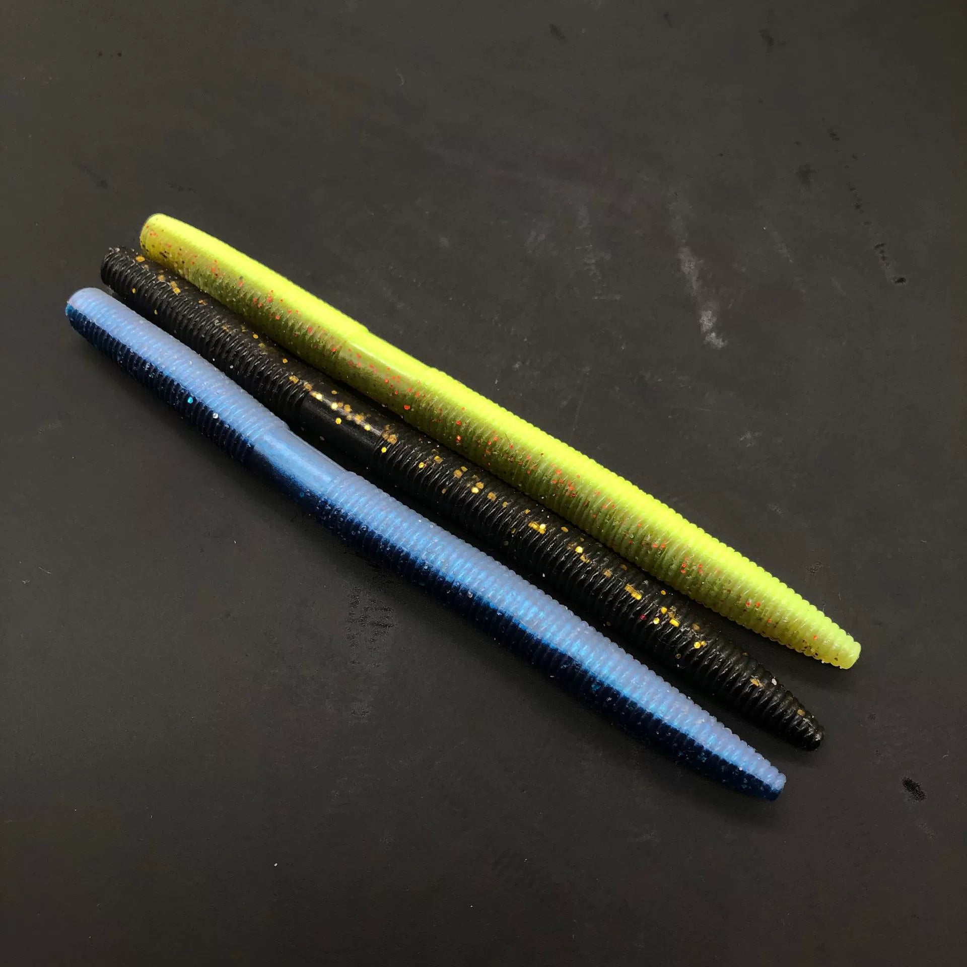 Soft plastic stick bait worms, blue, neon yellow, and black