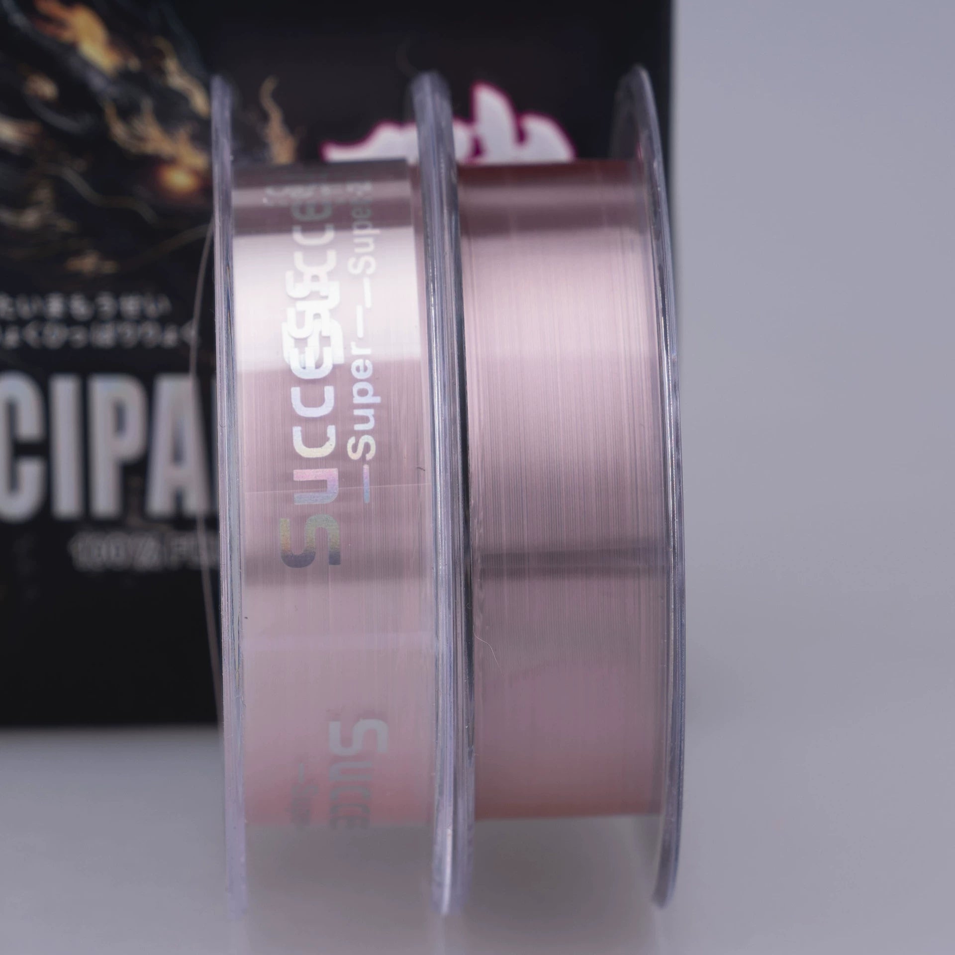 Close-up of pink leader line wound on clear spool, with black box behind
