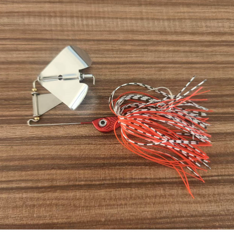 Skirted bladed jig lure with red spiky strands and silver blade on wooden board